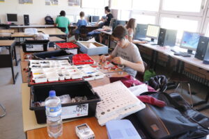 Ein Schüler arbeitet an einem Tisch auf dem viele elektronische Bauteile liegen.