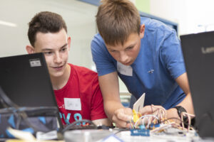 Zwei Jungs schauen konzentriert auf ihren Prototypen. Einer steck ein Kabel in den Mikrocontroller.