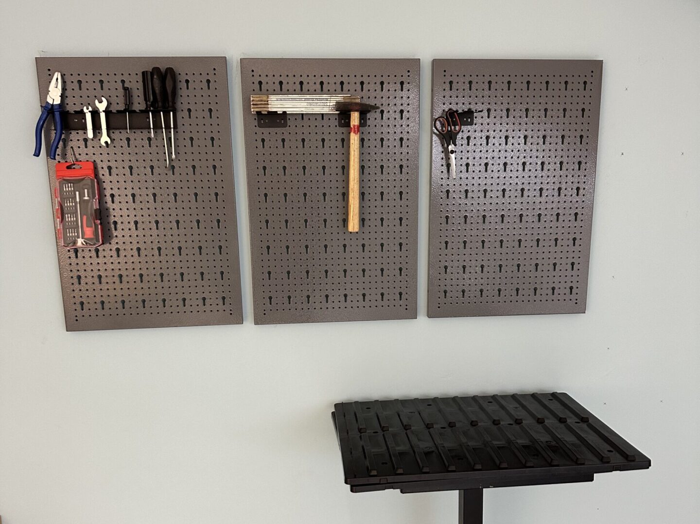An einer Wand sind unterschiedliche Werkzeuge befestig. Davor steht ein kleiner Tisch.
