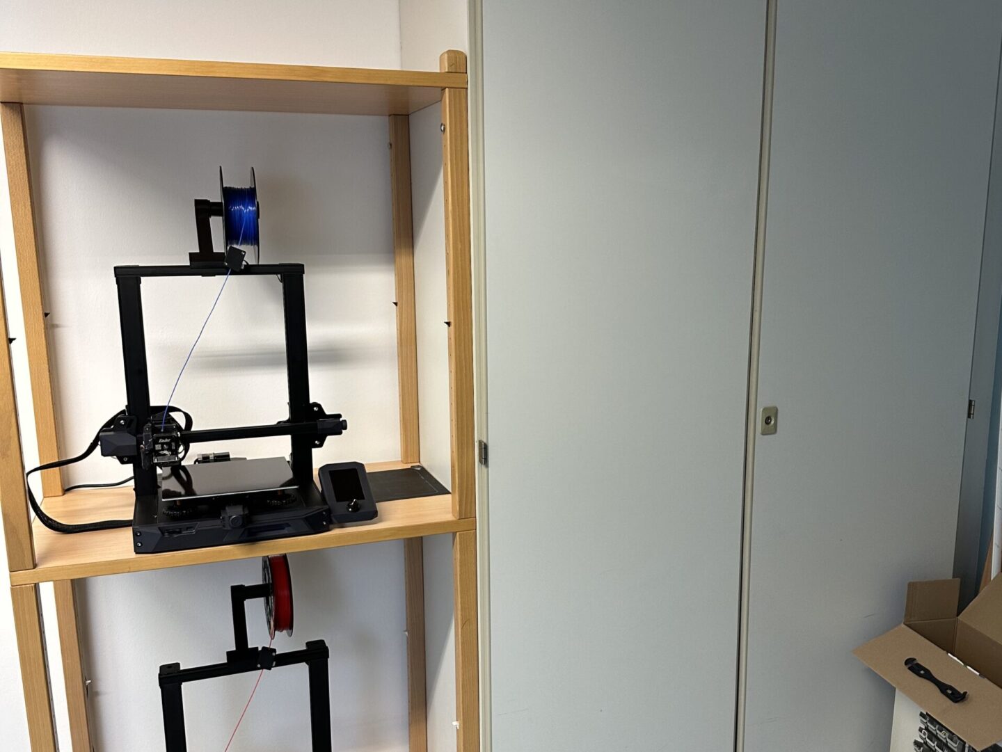 Zwei 3D-Drucker stehen in einem Regal.