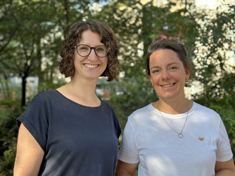 Zwei Frauen, die draußen vor grünem Hintergrund stehen