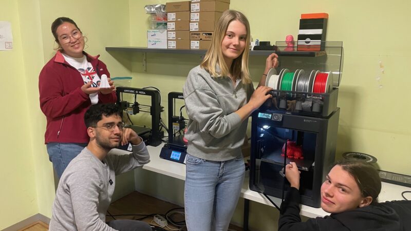 Vier Schüler*innen stehen im Maker Space ihrer Schule vor einem 3D-Drucker