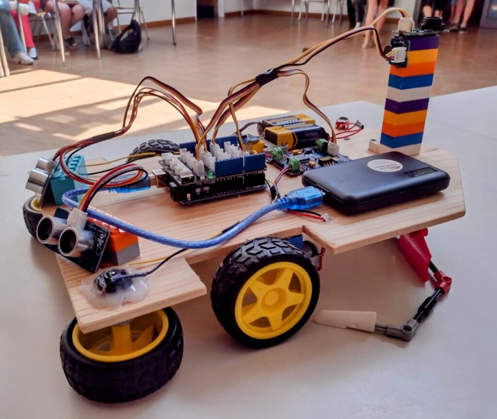 Ein Fahrzeug mit schwarzen Rädern, Legobauteilen und elektronischen Bauteilen